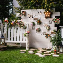 Wedding party. Beautiful unusual wedding decor. Rustic Style. Bench wall of flowers lanterns at the rustic wedding photo zone. Wedding concept
